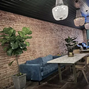 a dining room with a brick wall and blue couches