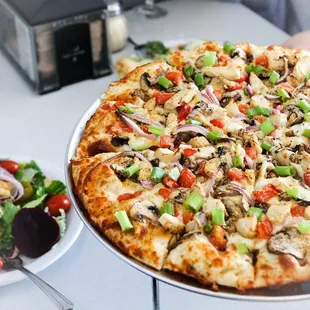 a plate of vegetables and a pizza