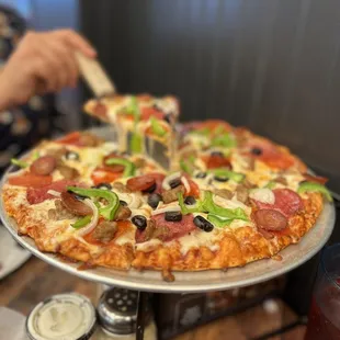 a person taking a slice of pizza
