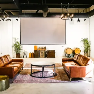 a large room with couches, tables, chairs, and a projector screen