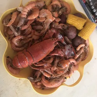 a bowl of lobster, corn, potatoes, and corn on the cob