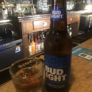 a bud light bottle and a glass on a bar counter