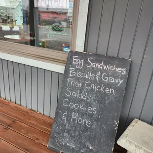 a chalkboard sign on the porch of a restaurant