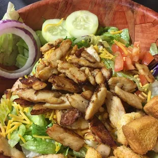 a salad with chicken, lettuce, tomatoes, cheese, onion, and croutons