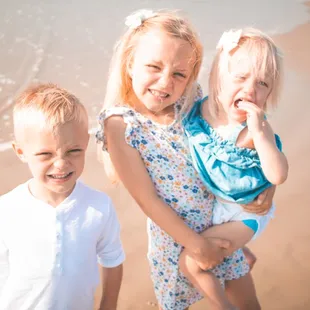 Children smiling for a photo on the beach with cinematic edits.