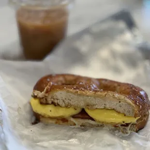 Bacon, egg, and cheese pretzel breakfast sandwich. Cold brew in the background.