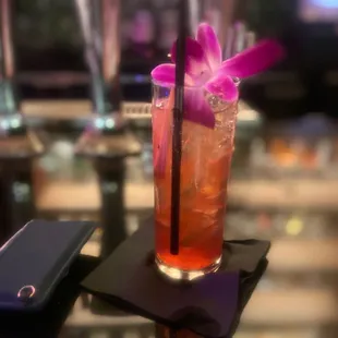 a cocktail with a purple flower