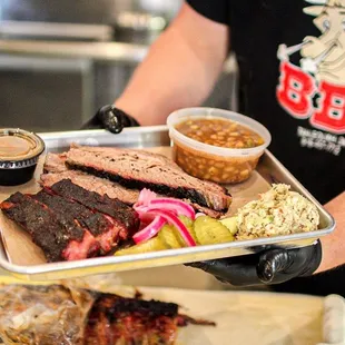  a man holding a tray of ribs and sides