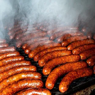  hot dogs cooking on a grill