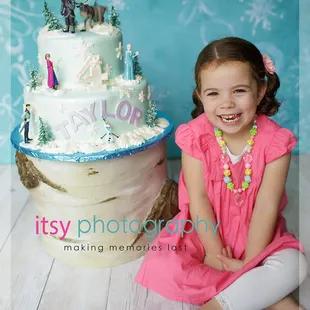 a little girl sitting in front of a cake