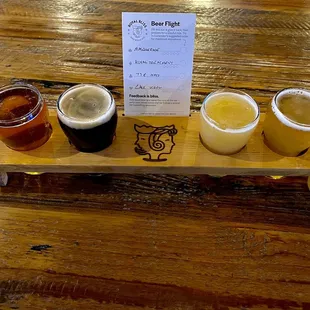 a flight of beers on a wooden tray