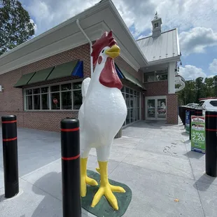 a chicken statue in front of a store