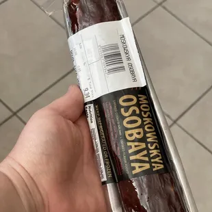 a hand holding a wrapped sausage