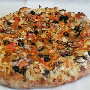 a pizza with olives, tomatoes, and onions