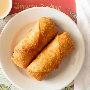 two fried spring rolls on a plate with dipping sauce