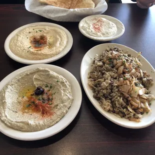Front: Hummus, Mujadaraha, 2nd row: Baba ghanoush, side of tzatziki, and pita
