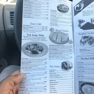 a hand holding a menu in a car