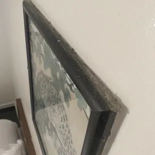Dust on the top of the wall hanging.
