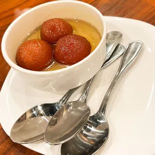 a bowl of gulaba and spoons