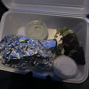 a takeout container with a salad and dressing