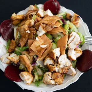 a plate of salad with chicken, lettuce, and beets