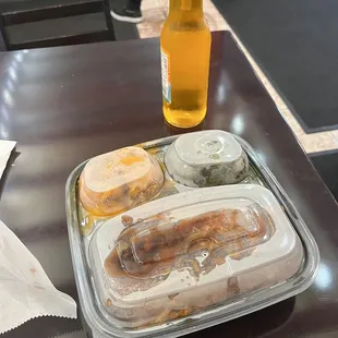 a hot dog with mustard, pickles, and a bottle of beer