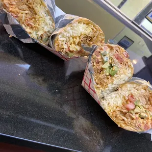 three burritos sitting on a counter