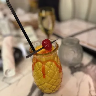 a pineapple cocktail with a cherry garnish