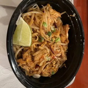 a bowl of noodles and a lime wedge