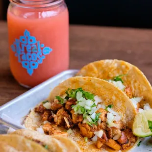 two tacoss on a plate with a drink in the background