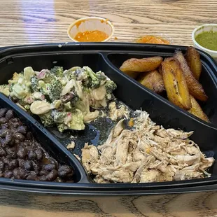Platter with shredded chicken, beans, broccoli salad, plantain and hot habanero and chimichurri sauces.