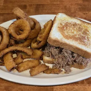 Rubbin Butts pulled pork sandwich on Texas toast with onion rings.