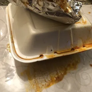 a half eaten burrito in a styrofoam container