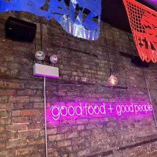 a brick wall with a neon sign that says good food good deal