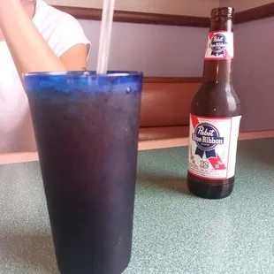 a woman sitting at a table with a cold beverage