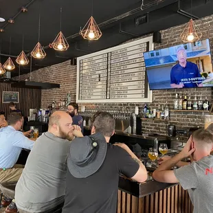 people sitting at a bar watching tv