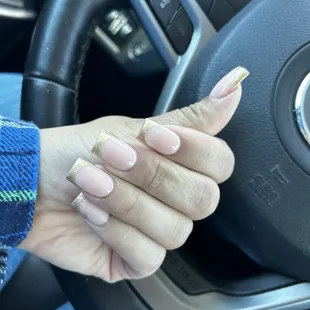 Full set acrylic nails, with a gold French tip.