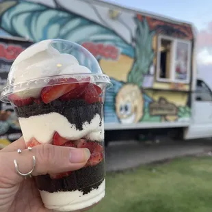 ws a hand holding a cup of dessert