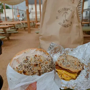 a hand holding a bagel sandwich
