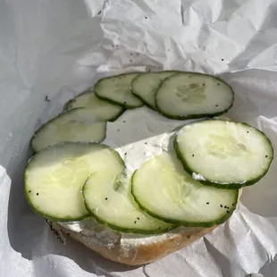 Poppyseed bagel with plain cream cheese and cucumbers