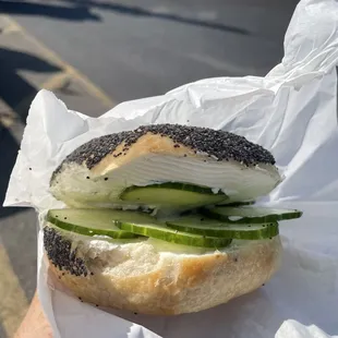 Poppyseed bagel with plain cream cheese and cucumbers