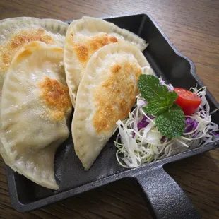 two dumplings on a plate with a side salad