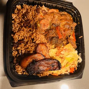 Brown stew chicken, rice and peas, plaintains, and cabbage
