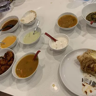 Assortment of chutneys, palak paneer, gobi manchurian, and a piece (about 1/5) of a dosa.