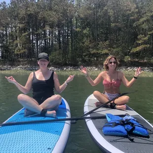 Two people seated on stand up paddle boards in Rudee Inlet, Virginia Beach, VA