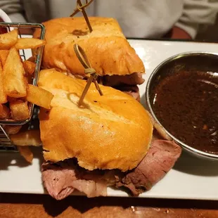 a roast beef sandwich with fries and dipping sauce