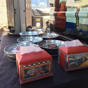 Condiment table. They have little packets of sirachi sauce, malt  vinegar, ketchup, salt, and pepper.