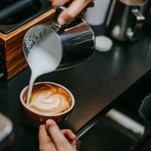 a person pouring milk into a cup of coffee