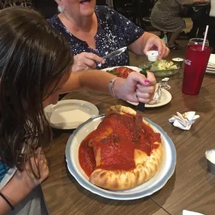 a woman and a child eating a pizza