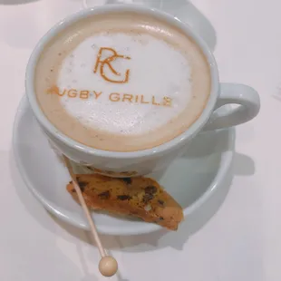 a cup of coffee with a biscuit on a saucer